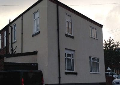 angled view of a newly primed and reinforced wall with Cream rendered finish